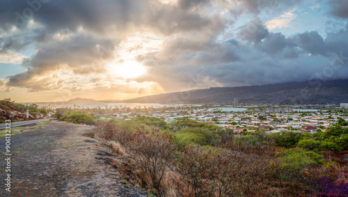 Hawaiian asphalt road trip with a view to a small village during sunset phase with rain clouds at the background photo