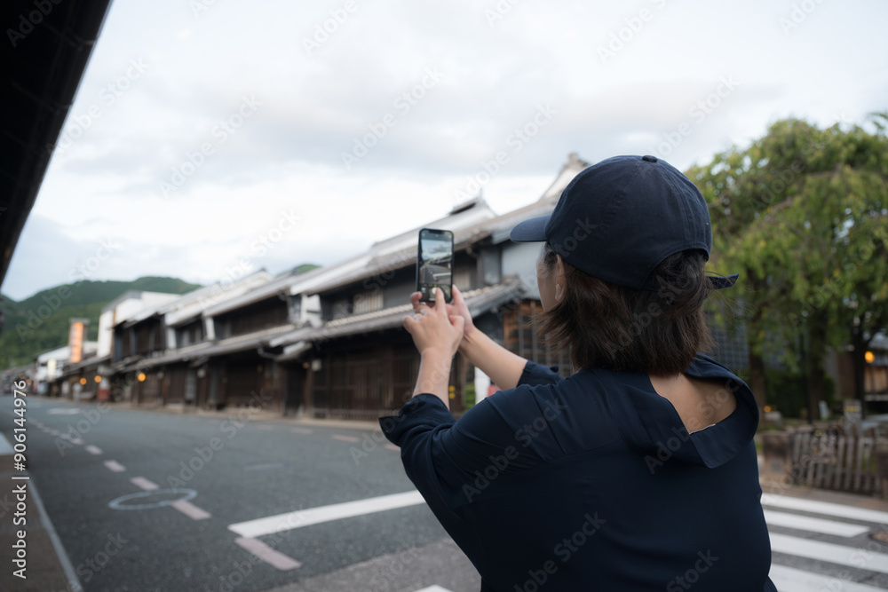 Obraz premium 岐阜県美濃のうだつの町並みをスマホで撮影する観光する女性