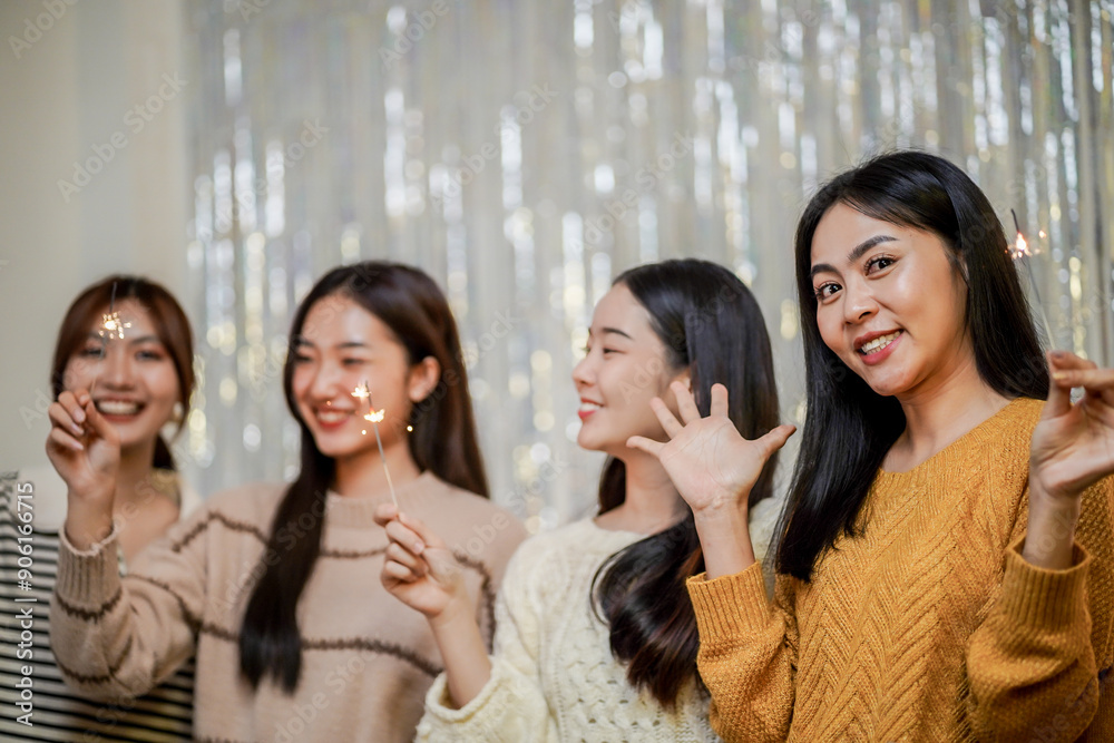 Cheerful friends enjoying home Birthday holiday party. Asian Friends hold lights with sparkling Sparkler celebrating Christmas or New Year eve party. Cheerful friends enjoying home Birthday holiday party. Asian Friends hold lights with sparkling Sparkler celebrating Christmas or New Year eve party.