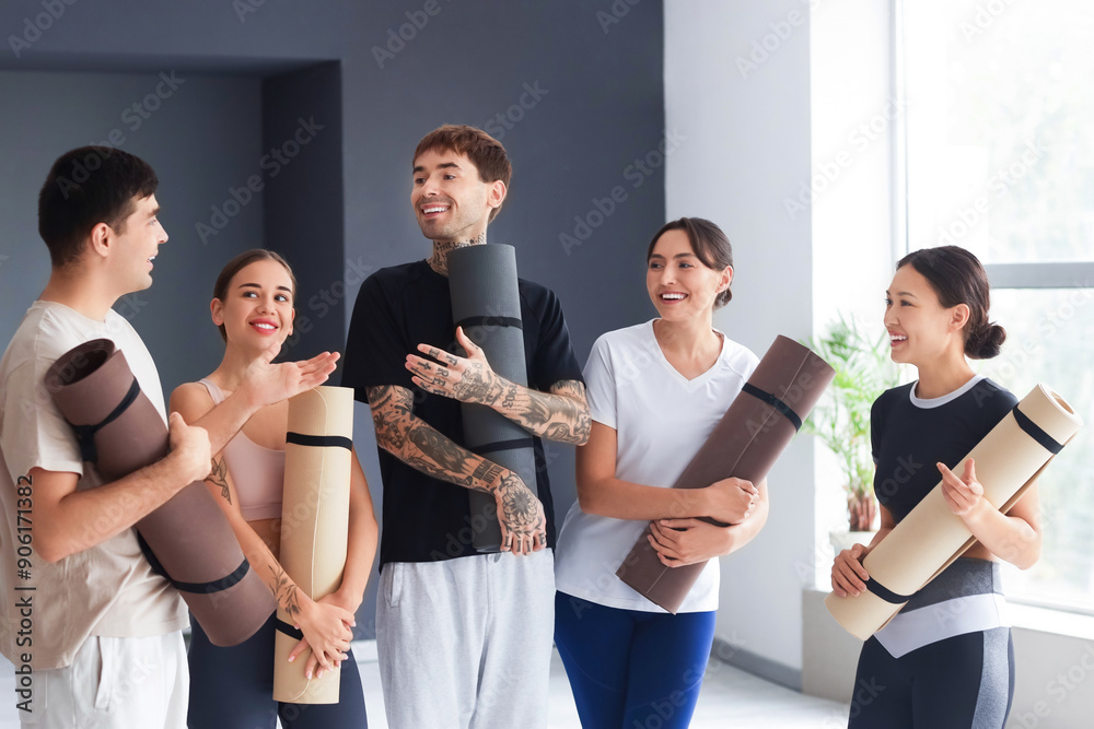 Group of sporty young people with yoga mats in gym Group of sporty young people with yoga mats in gym