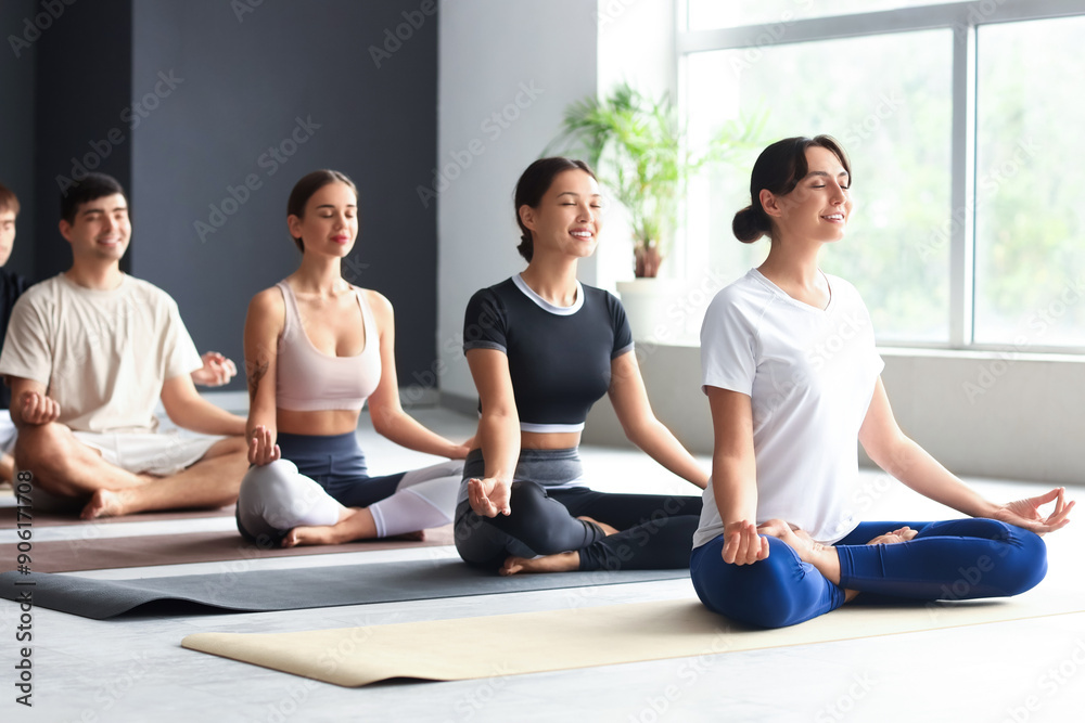 Group of sporty young people meditating in gym Group of sporty young people meditating in gym