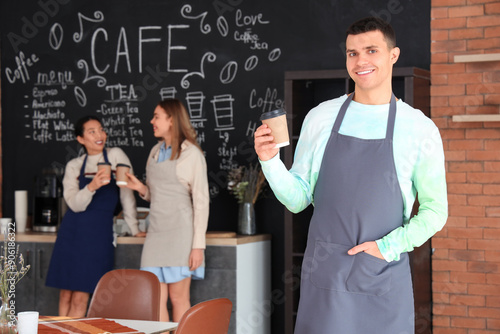 Male barista with coffee cup in cafe