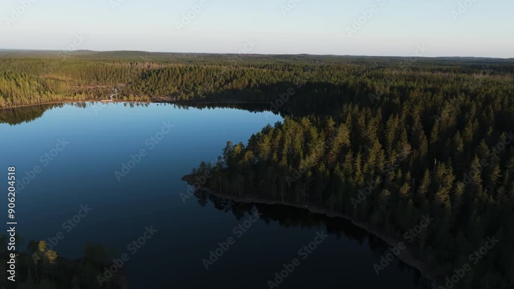 Aerial flyover of a reflecting lake, and wild nature of Finland, sunny evening