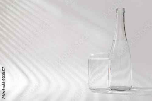 Foto Bottle of clean water and glass on white background