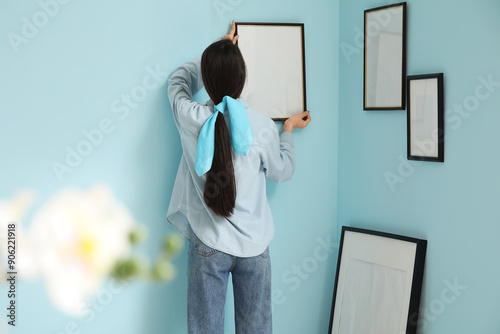 Young woman hanging picture...
