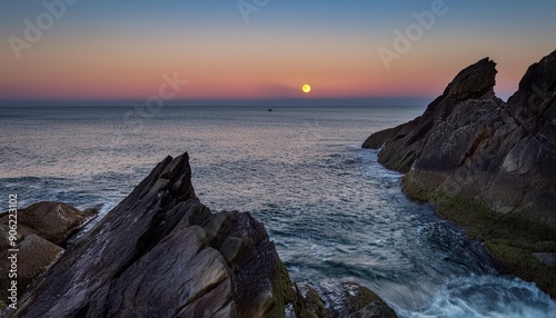 Full moon setting through the rocking just off Holywell Bay, Newquay, Cornwall, UK photo