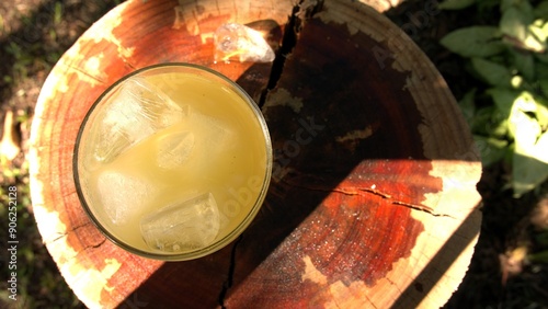 A top view of a pineapple juice glass mixed with mint and ice cubes. A big glass of juice on the table. A glass of pineapple juice. A mint juice glasss. A fruit jar outdoors