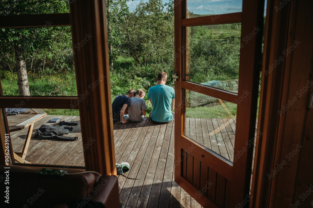 Dad with two boys on cabin terrace in Iceland, serene outdoor scene Dad with two boys on cabin terrace in Iceland, serene outdoor scene