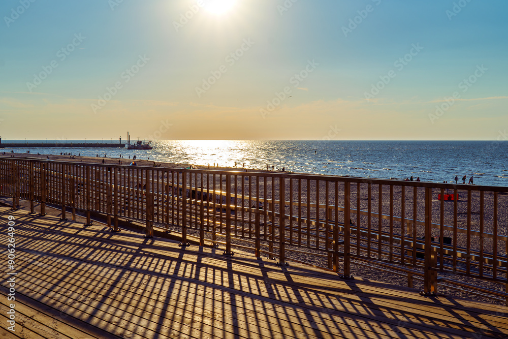 View from the wooden observation deck towards the sea. Sunset. Shadows of steel balustrades. Leba, Baltic sea, Poland