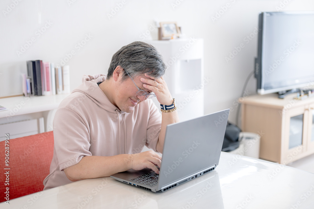 PCと頭を抱える中年男性 PCと頭を抱える中年男性