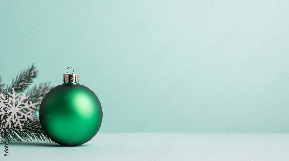 Minimalist Christmas background featuring a single green ornament, subtle snowflake pattern, light blue gradient backdrop, empty space for text 