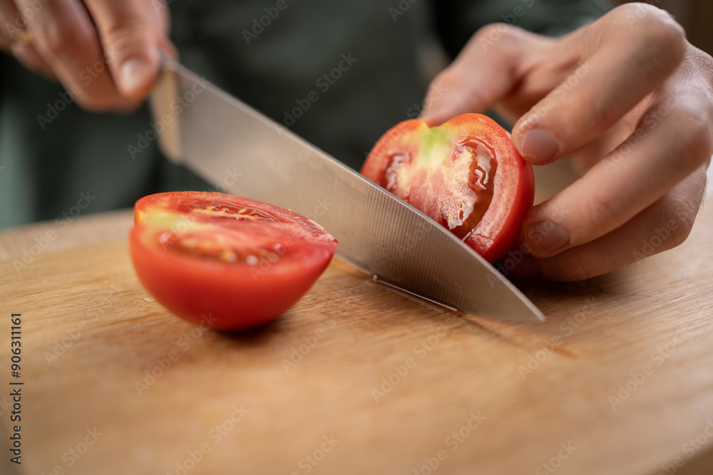 Chef cutting red tomato with a large knife, selective focus, concept of home cooking Chef cutting red tomato with a large knife, selective focus, concept of home cooking