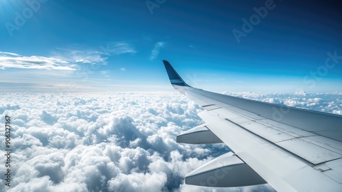 Airplane wing close-up with a backdrop of a clear blue sky and fluffy clouds, offering a panoramic view ideal for aviation content.