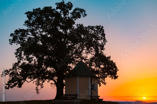 Alpine sunrise view with silhouettes of a tree and a chapel at Luitpoldchapel, Samerberg, Chiemgau, Rosenheim, Bavaria, Germany photo