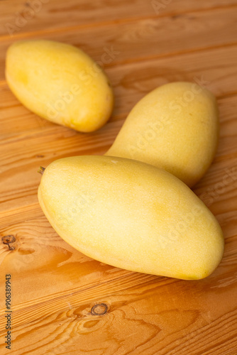 Delicious ripe juicy mangos on wooden table, top view