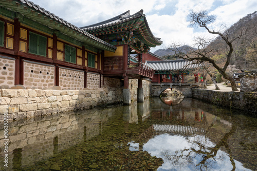 Suncheon-si, Jeollanam-do, South Korea - April a 2022: Spring view of brook and Imgyeongdang House and Buddhist sanctuary with arch stone bridge at Songgwangsa Temple against Jogyesan Mt. 