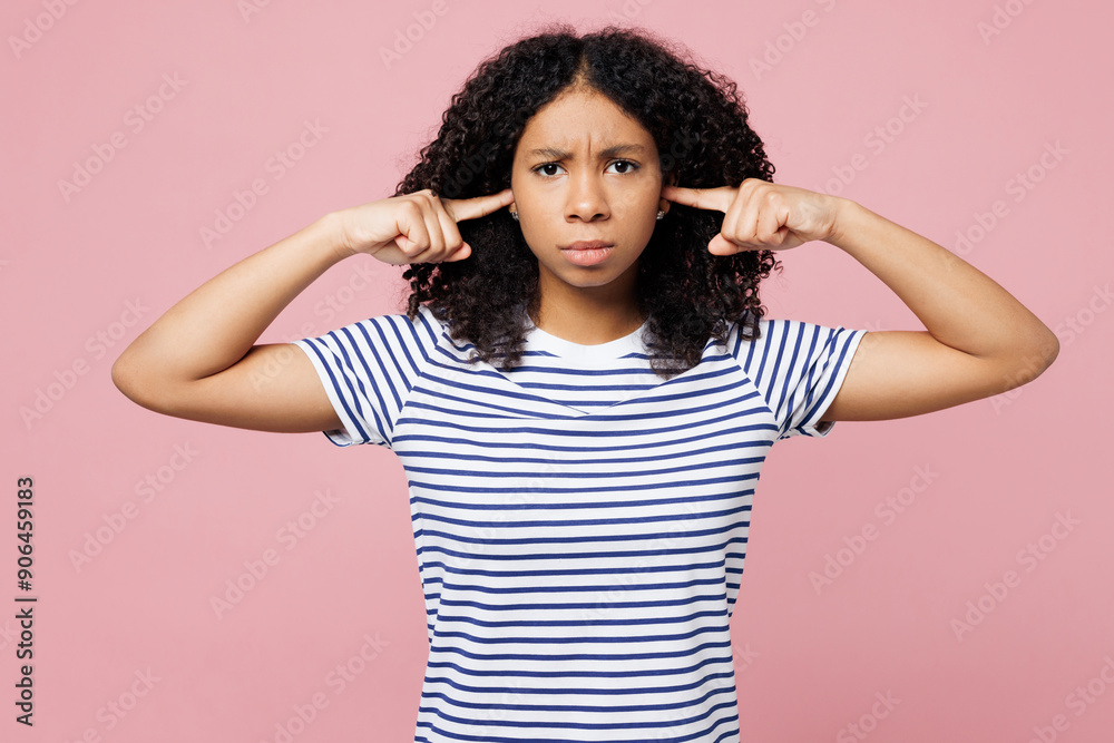 Little sad kid teen girl wearing blue striped t-shirt casual clothes cover ears with hands fingers do not want to listen scream isolated on plain pink background studio . Childhood lifestyle concept. Little sad kid teen girl wearing blue striped t-shirt casual clothes cover ears with hands fingers do not want to listen scream isolated on plain pink background studio . Childhood lifestyle concept.