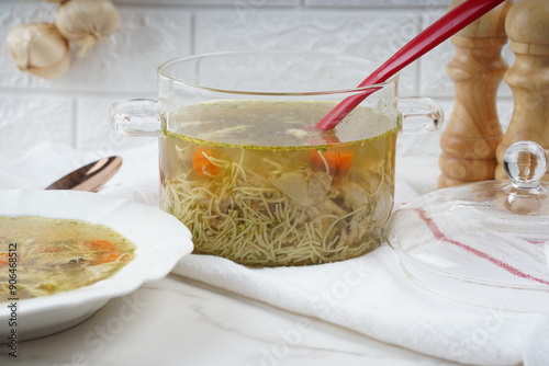 Chicken soup, chicken broth, with pieces of chicken and vegetables. Chicken bouillon in transperent glass pot