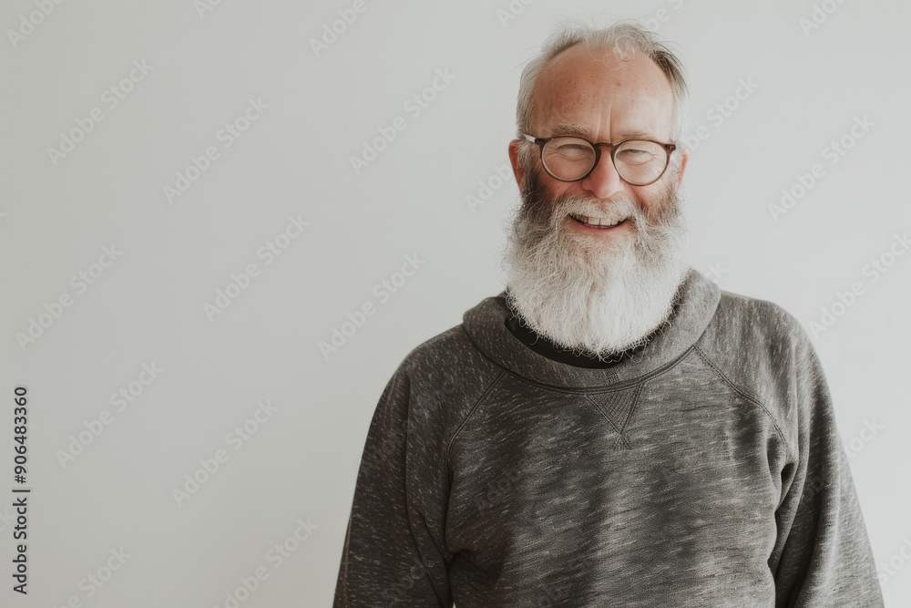 A joyful elderly man with glasses and a white beard, dressed in a gray sweater, stands against a plain backdrop, showcasing a radiant smile. A joyful elderly man with glasses and a white beard, dressed in a gray sweater, stands against a plain backdrop, showcasing a radiant smile.