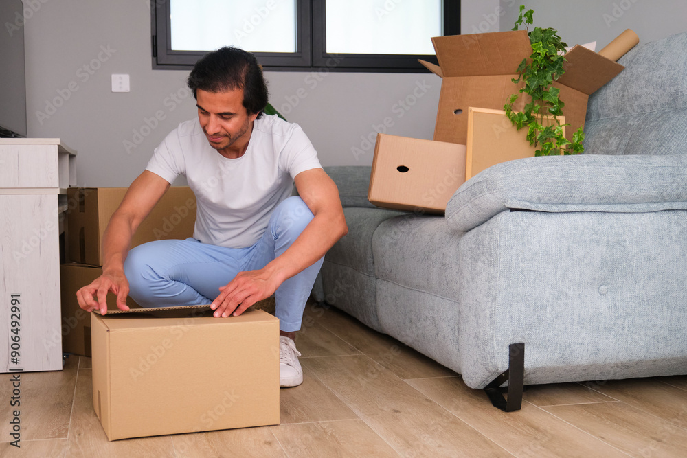 Indian man is carefully packing his belongings into cardboard boxes, preparing for a house move Indian man is carefully packing his belongings into cardboard boxes, preparing for a house move