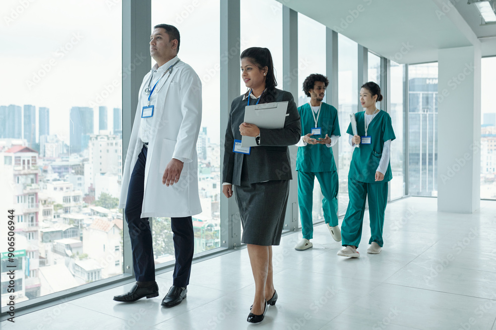 Manager of clinic talking to doctor while they walking along the hospital corridor Manager of clinic talking to doctor while they walking along the hospital corridor