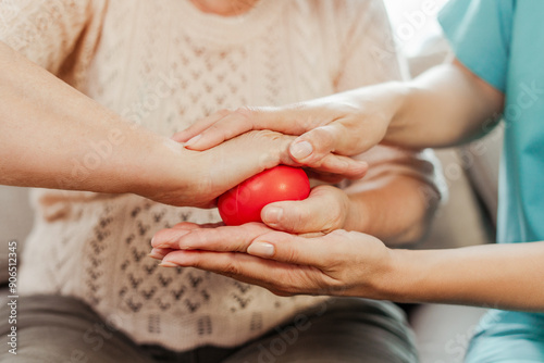 Photos Nurse assisting elderly patient with hand physical therapy using red stress ball