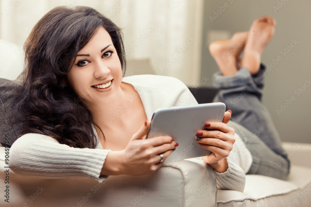 Fototapeta premium Young woman relaxing on sofa using digital tablet at home