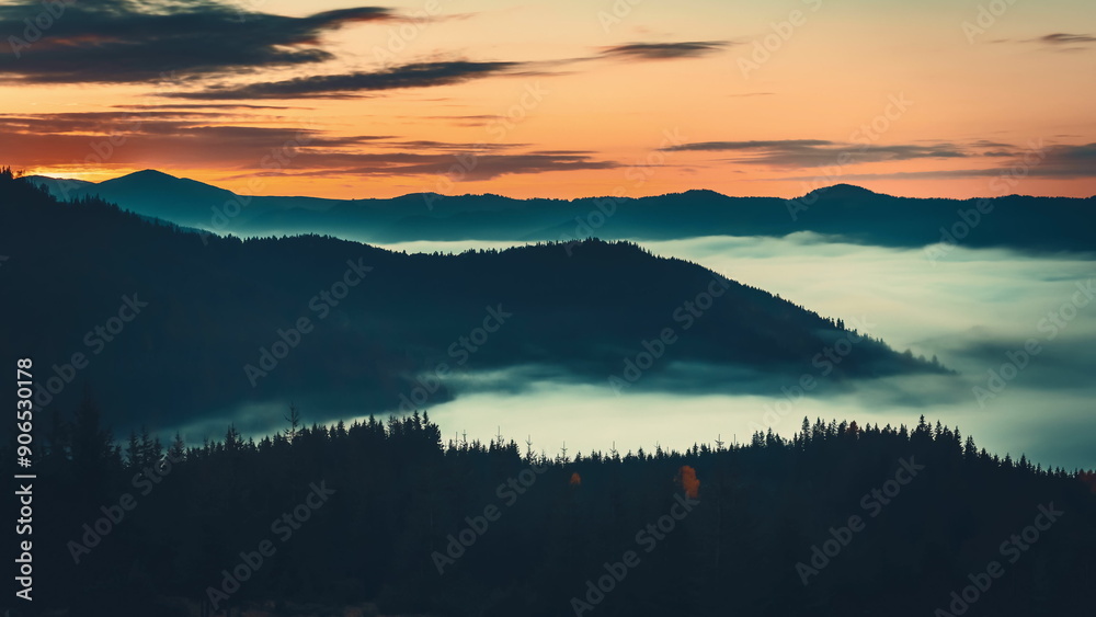 Fototapeta premium The sun's first rays light up carpathian peaks, casting shadows on slopes with fog adding mystery and serenity