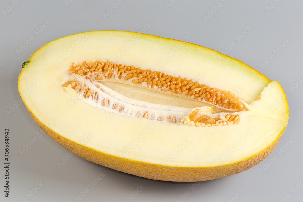 Half of yellow melon with seeds on a gray background Half of yellow melon with seeds on a gray background