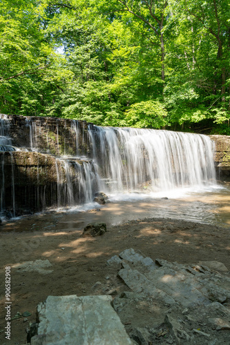 A beautiful view of a waterfall hidden away in a lush and green forest.