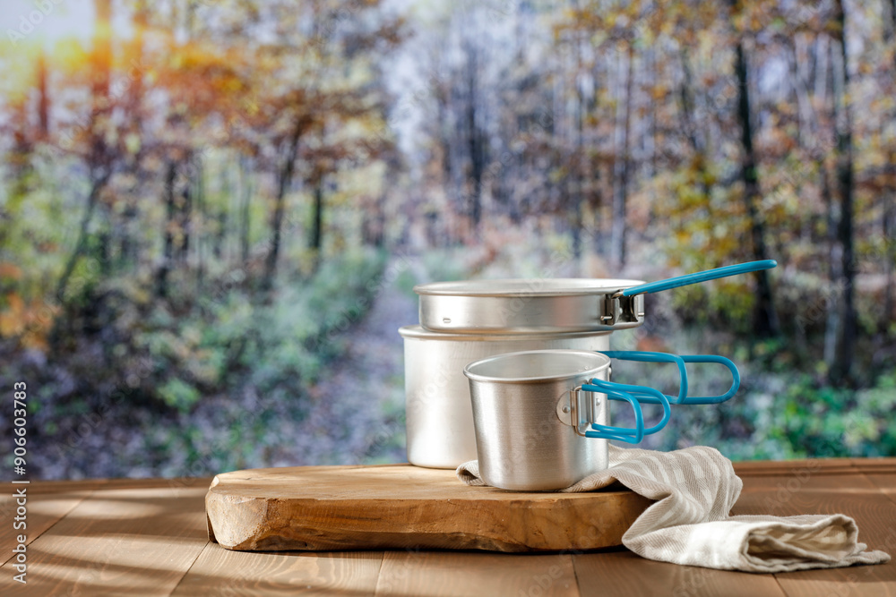Aluminium dishes and mess tin on wooden autumn table and autumn trees in forest background. Aluminium dishes and mess tin on wooden autumn table and autumn trees in forest background.