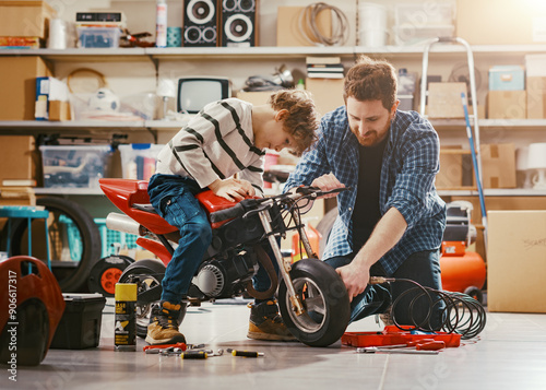 Obraz na plátne Father checking the son's motorbike in the garage