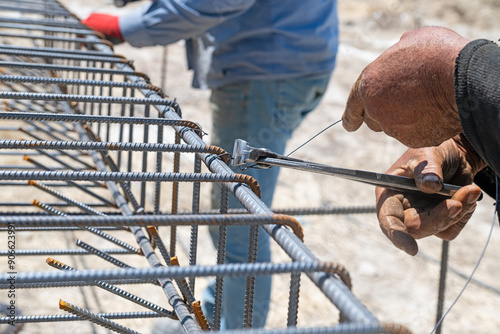 Workers use steel lacing wire to attach steel bars to reinforcing bars. Close-up. Reinforced concrete structures - knitting a metal reinforcing cage photo