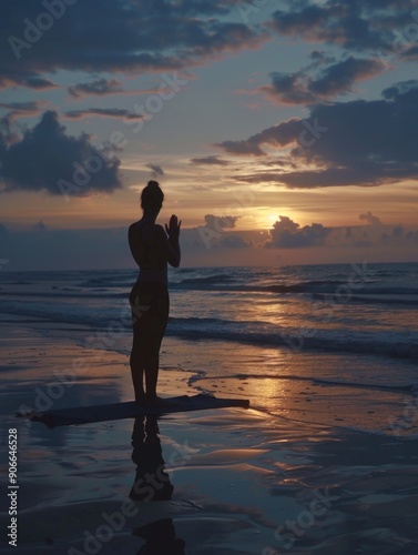 A woman stands alone on the beach at sunset with the ocean in the background #906646528