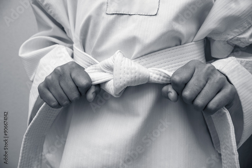 black and white Kid in martial arts taekwondo or karate dobok uniform and holding belt