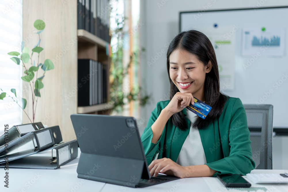 A woman is sitting at a desk with a laptop and a credit card in her hand A woman is sitting at a desk with a laptop and a credit card in her hand