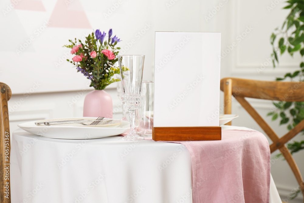 Menu holder, clean dishware and vase with beautiful flowers on white table in restaurant