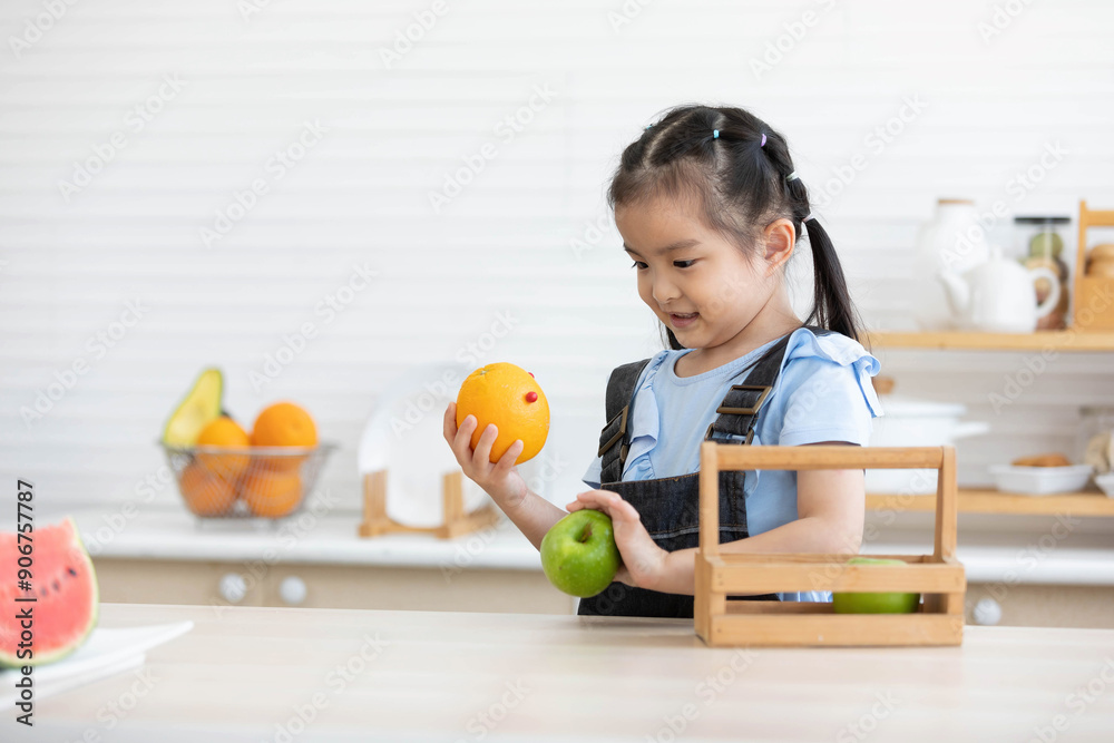 cute asian little child girl holding green apples in the kitchen cute asian little child girl holding green apples in the kitchen
