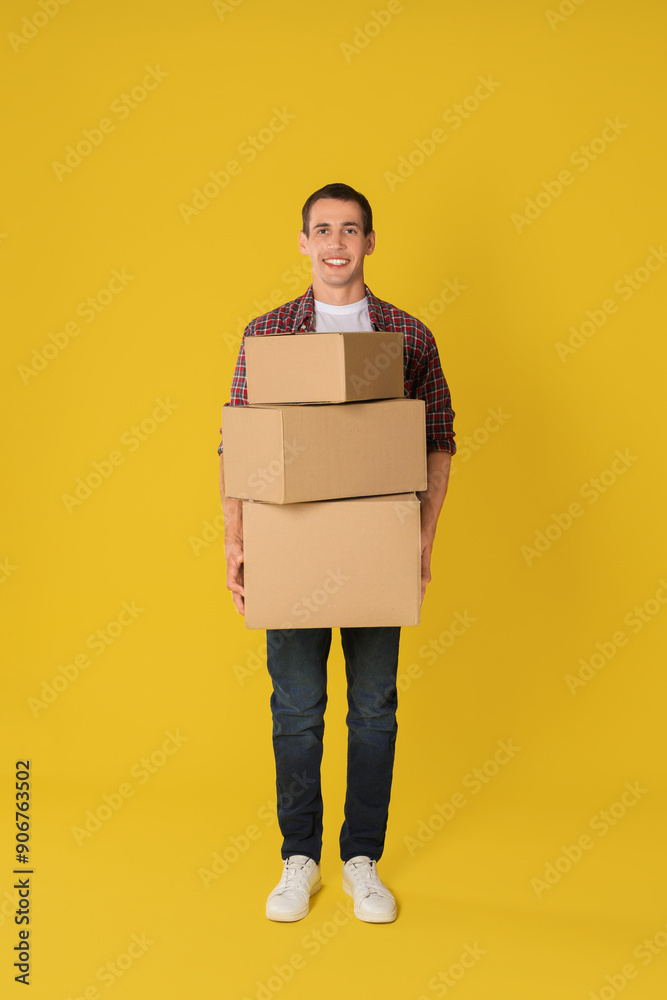 Moving into new house. Man with cardboard boxes on yellow background Moving into new house. Man with cardboard boxes on yellow background