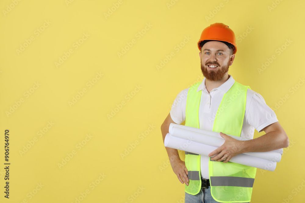 Engineer in hard hat with drafts on yellow background, space for text Engineer in hard hat with drafts on yellow background, space for text