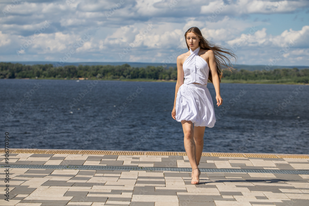 Young beautiful woman in a summer dress walking along the embankment Young beautiful woman in a summer dress walking along the embankment
