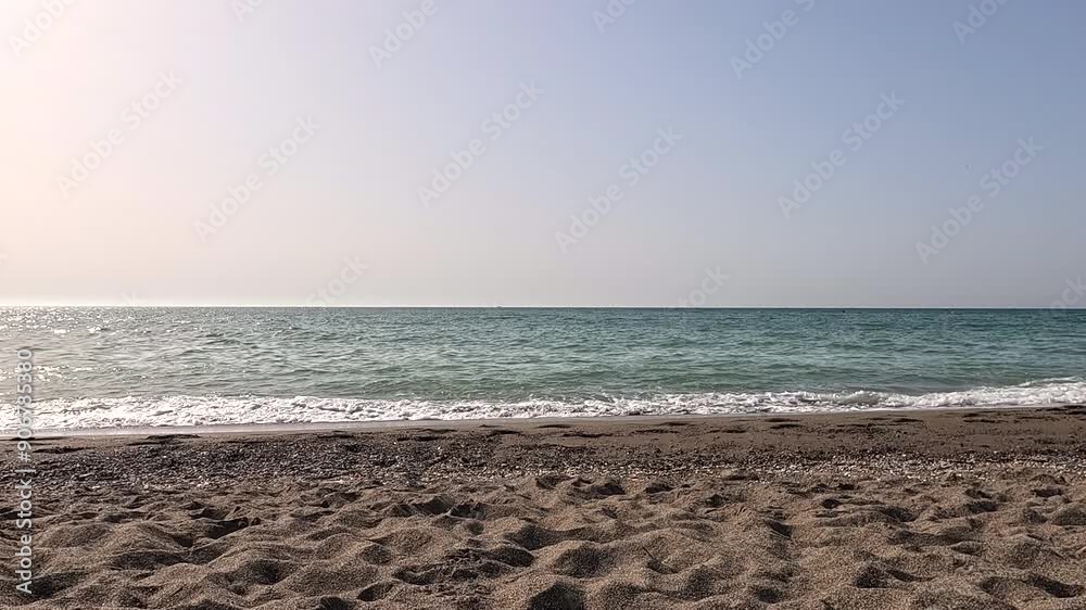timelapse , cámara rápida, en la playa con el mar mediterráneo en Málaga, con movimiento de pequeñas olas en la orilla y arena fina  y aviones que pasan por el cielo