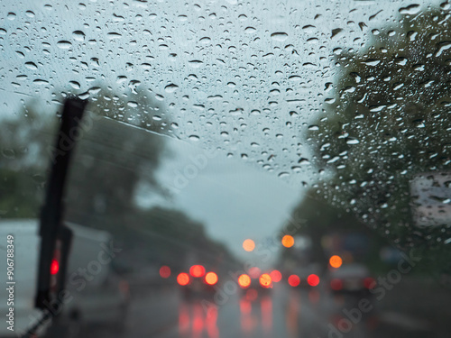 Obraz na płótnie Closeup of raindrops on a windshield, blurry wipers cleaning the glass, road traffic with blurry car lights. View from the driver's seat. w salonie