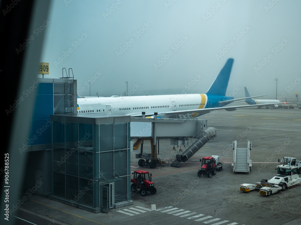 Jetway (telescopic air bridge) parked near the door of the airplane connecting it with terminal gate in Boryspil International airport, Kyiv. Tractors, tow tractor and boarding stairs staying around.