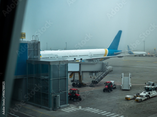 Obraz na płótnie Jetway (telescopic air bridge) parked near the door of the airplane connecting it with terminal gate in Boryspil International airport, Kyiv. Tractors, tow tractor and boarding stairs staying around. w salonie