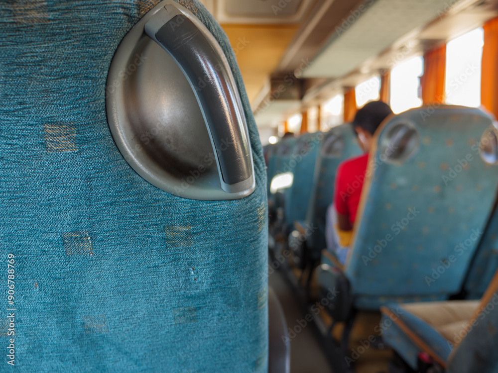 Closeup of a hand grip of a passenger seat in a bus riding from one town to another. Person sitting on the background.