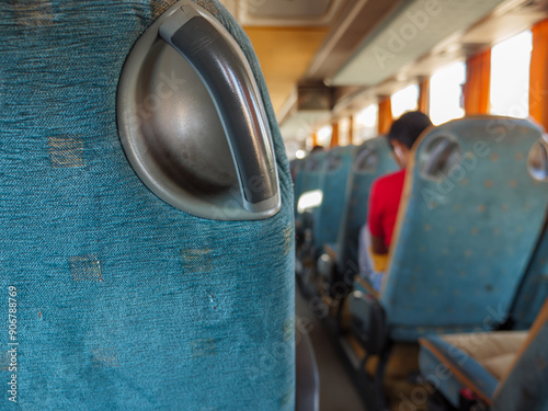 Obraz na płótnie Closeup of a hand grip of a passenger seat in a bus riding from one town to another. Person sitting on the background. w salonie