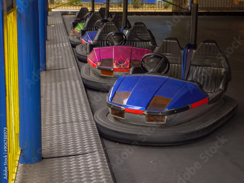 Obraz na płótnie Electric colorful old-fashioned bumper cars for two standing in a row in a city amusement park. Traditional family entertainment and active leisure time outdoors. w salonie