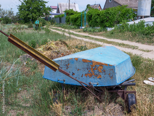 Obraz na płótnie Old abandoned boat with rust and peeling off paint lays overturned upside down by the side of the country earthy road. w salonie