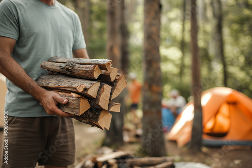 Outdoor camping concept with a man holding a pile of firewood photo